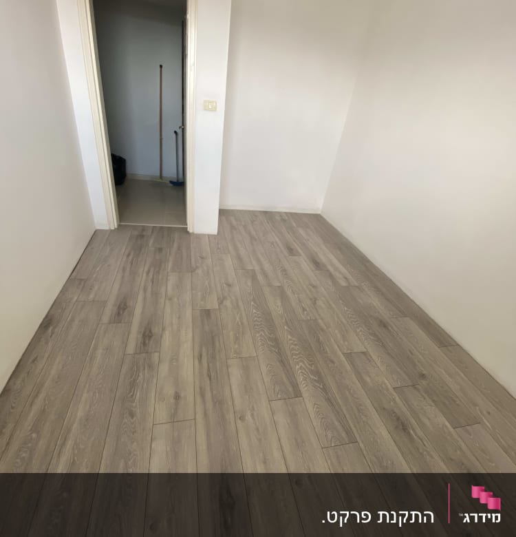 רצפת פרקט עץ בחדר ריק עם דלת פתוחה